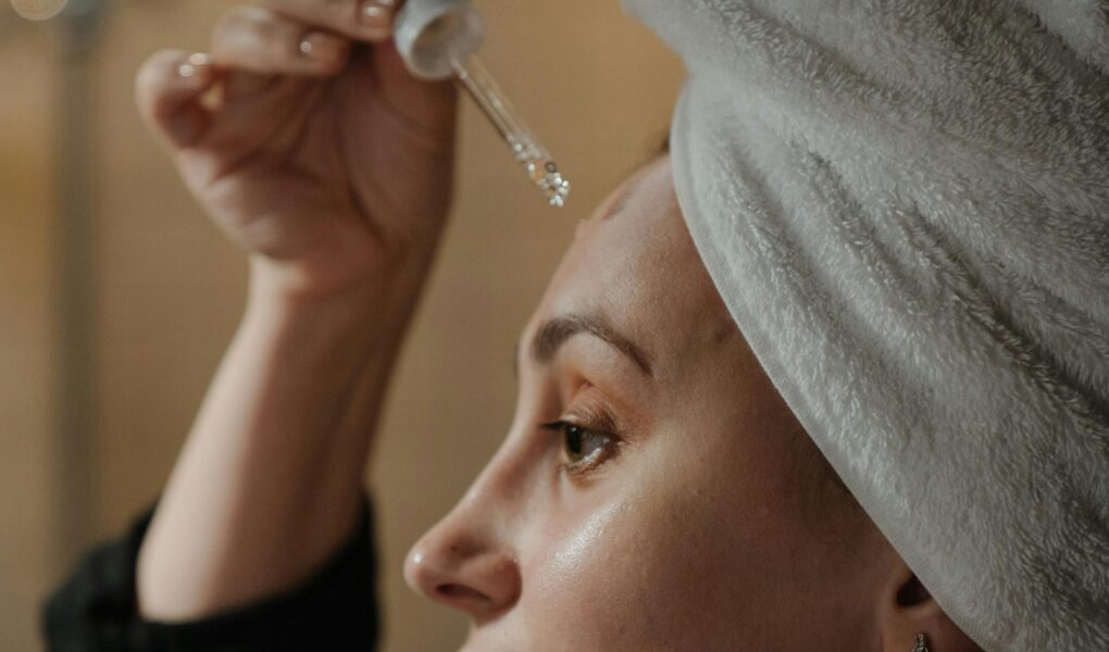 Mulher aplicando os produtos anti-idade, vitamina C, ácido hialuronico, serum, niacinamida.