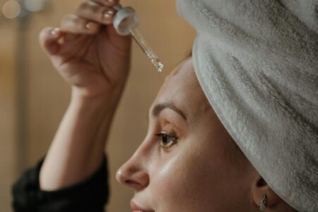 Mulher aplicando os produtos anti-idade, vitamina C, ácido hialuronico, serum, niacinamida.